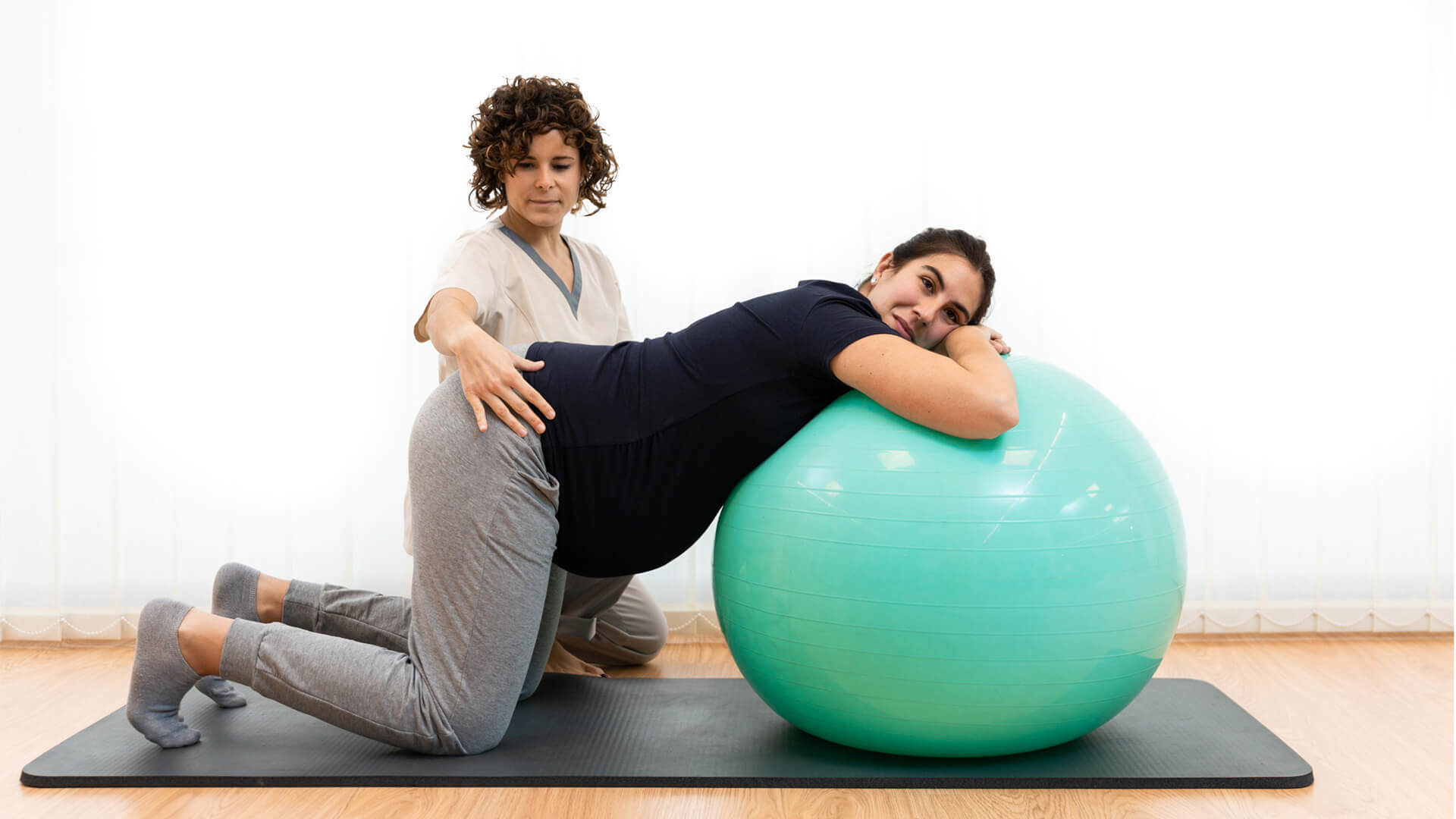 Fisioterapeuta com senhora grávida em exercício com bola de pilates